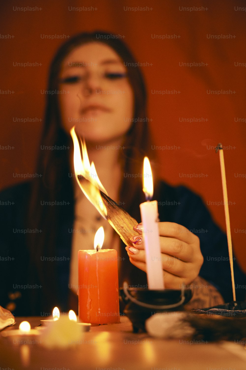 uma mulher acendendo uma vela em uma mesa