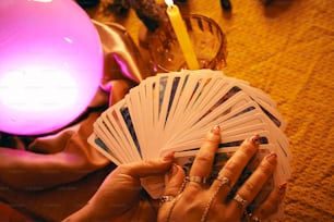 Una mujer sosteniendo una baraja de cartas junto a una vela