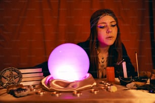 Une femme assise à une table avec une boule rougeoyante
