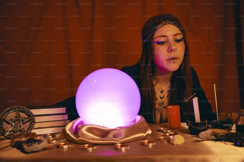 a woman sitting at a table with a glowing ball