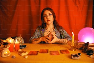 a woman sitting at a table surrounded by candles