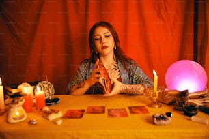 a woman sitting at a table surrounded by candles