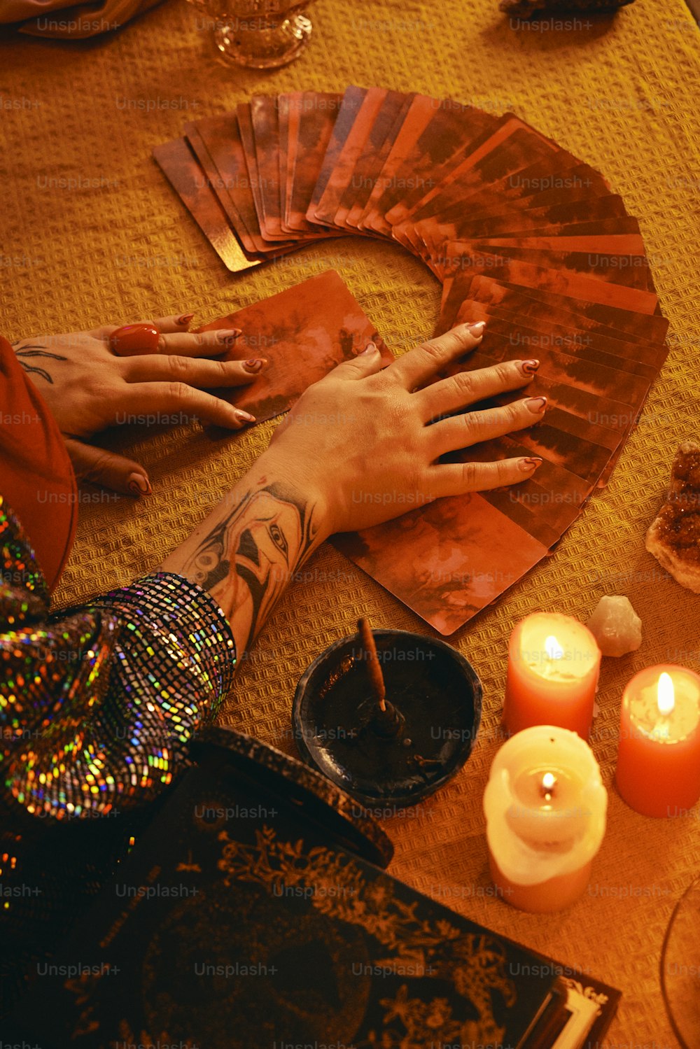 a person's hands on a table surrounded by candles