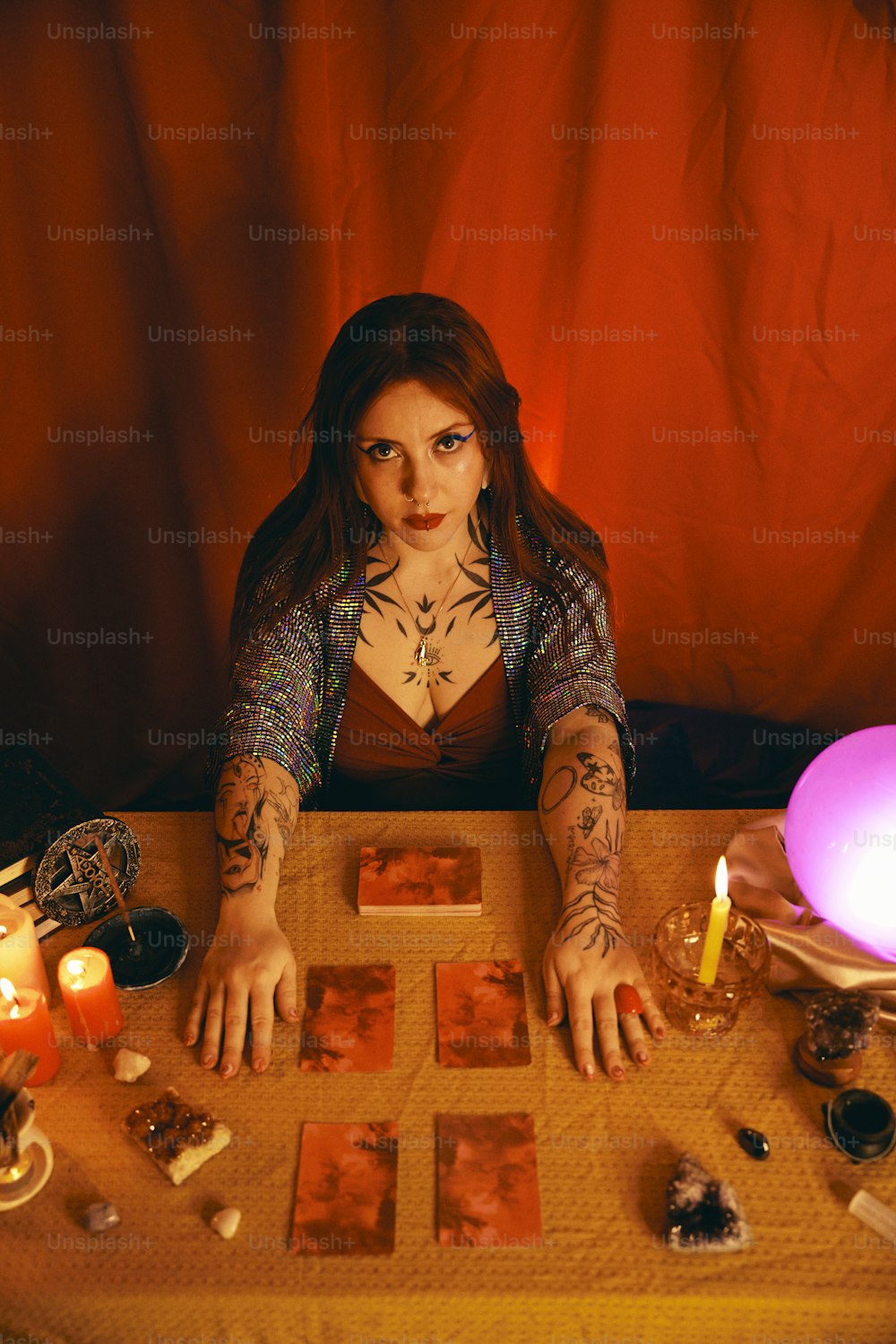 Una mujer sentada en una mesa con tarjetas y velas