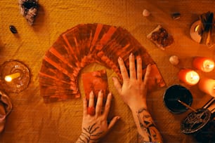 Las manos de una persona sobre una mesa con un ventilador y velas