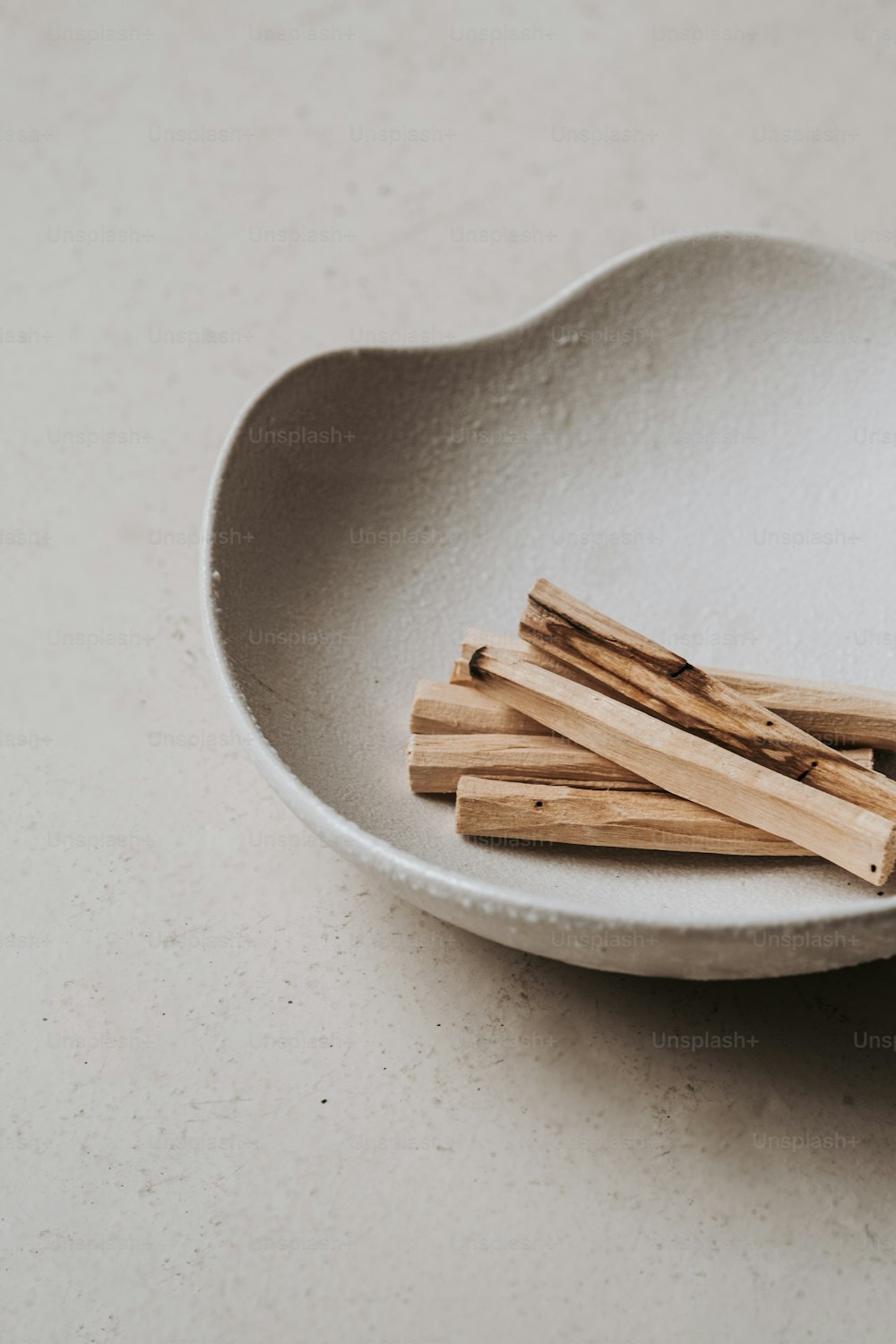 a white bowl filled with wooden sticks on top of a table