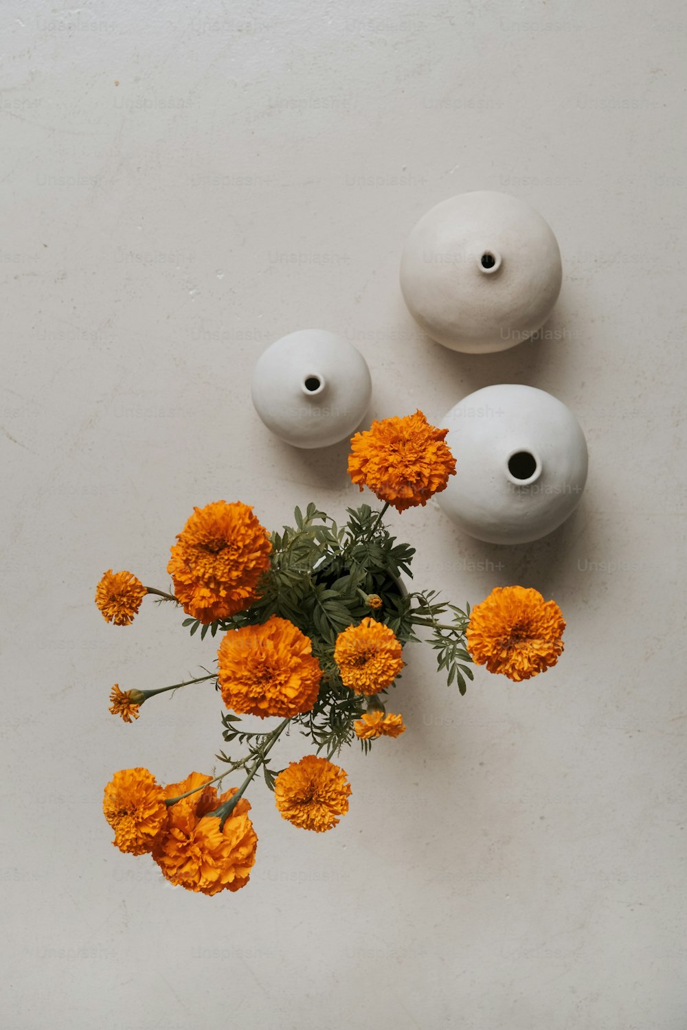 a bunch of orange flowers sitting next to two white vases