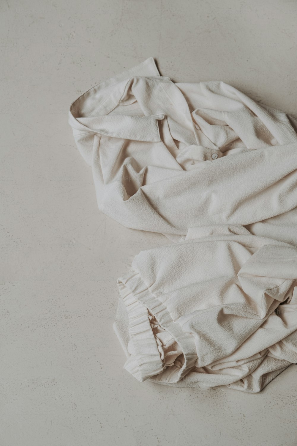 a white shirt laying on top of a white floor