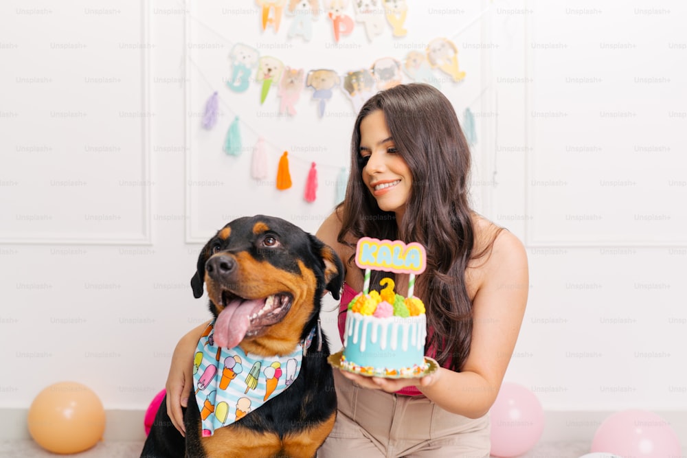 a woman holding a cake with a dog sitting next to her