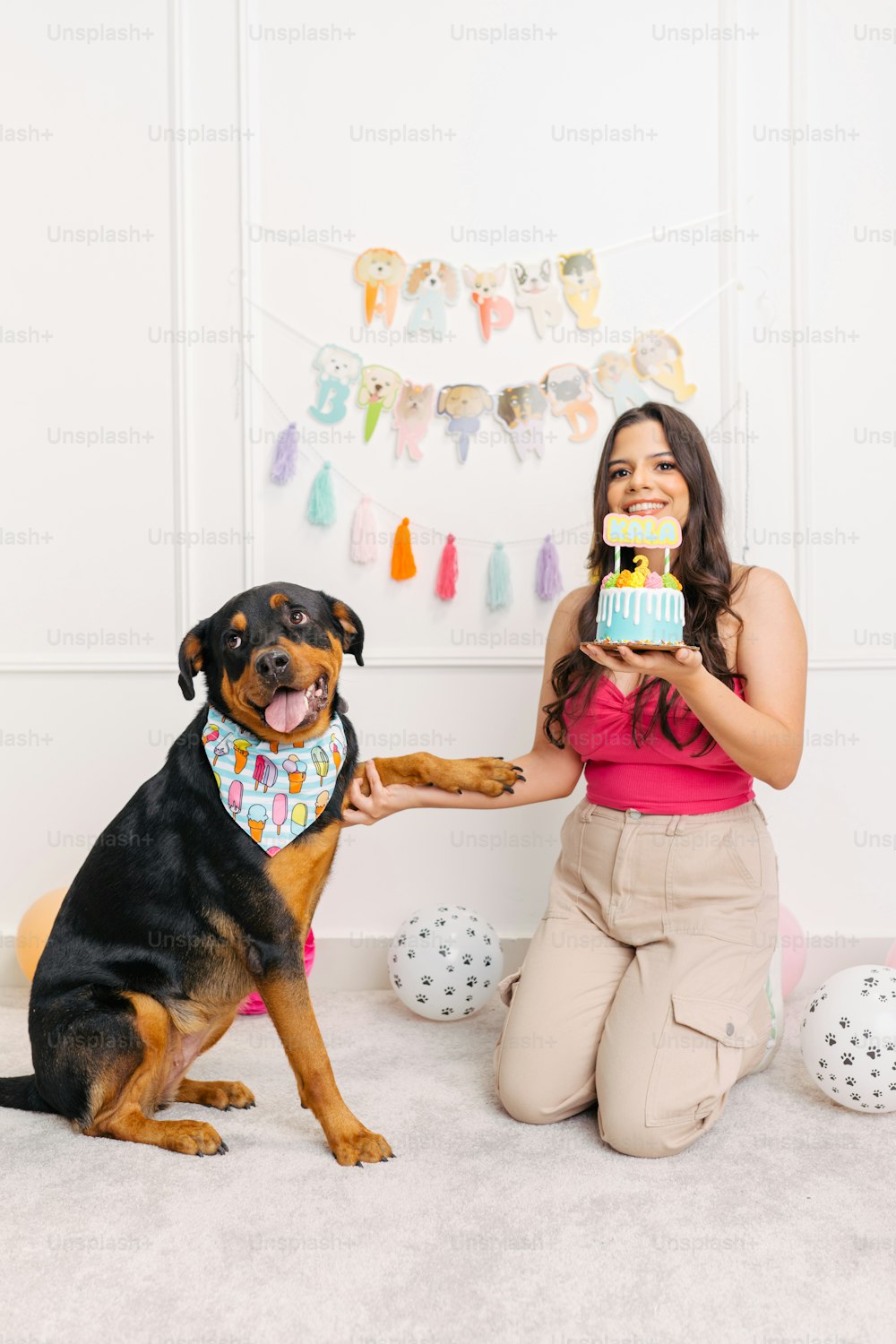 a woman sitting on the floor with a dog holding a cake