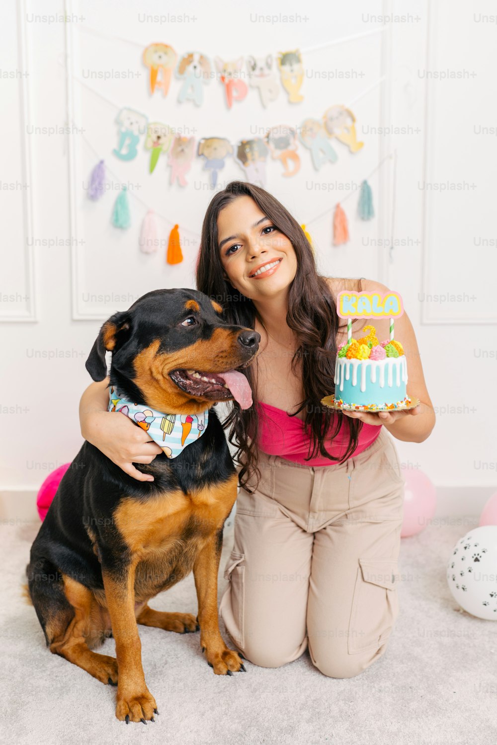 Una mujer sosteniendo un pastel de cumpleaños junto a un perro
