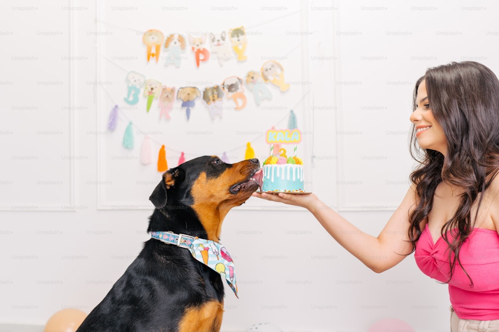 Una mujer alimentando a un perro con un pastel de cumpleaños