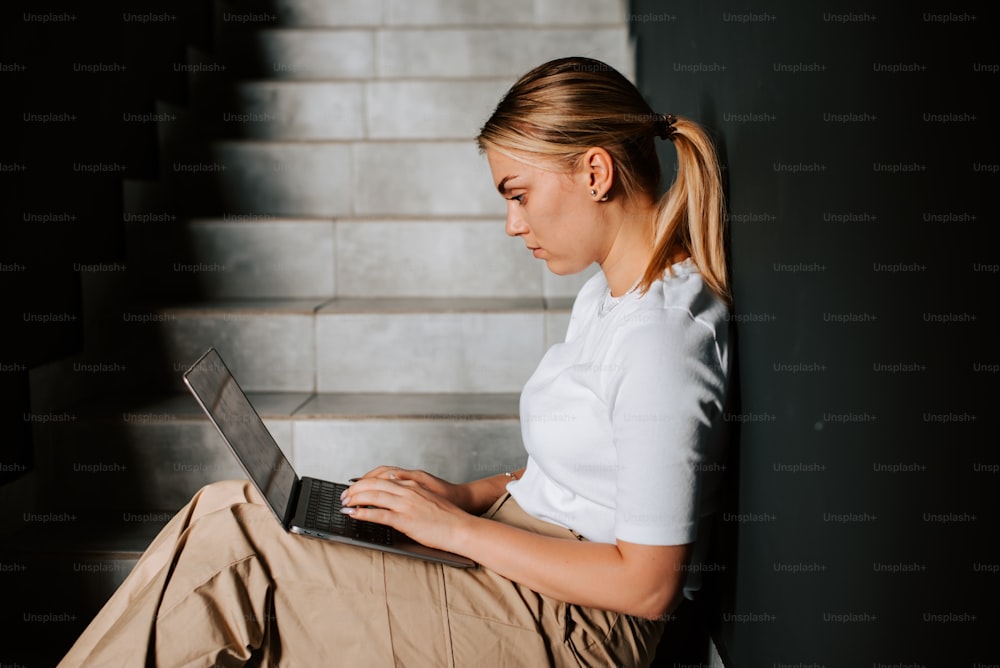 uma mulher sentada nos degraus usando um computador portátil