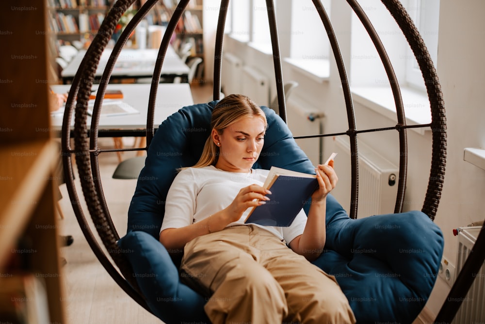 uma mulher sentada em uma cadeira lendo um livro