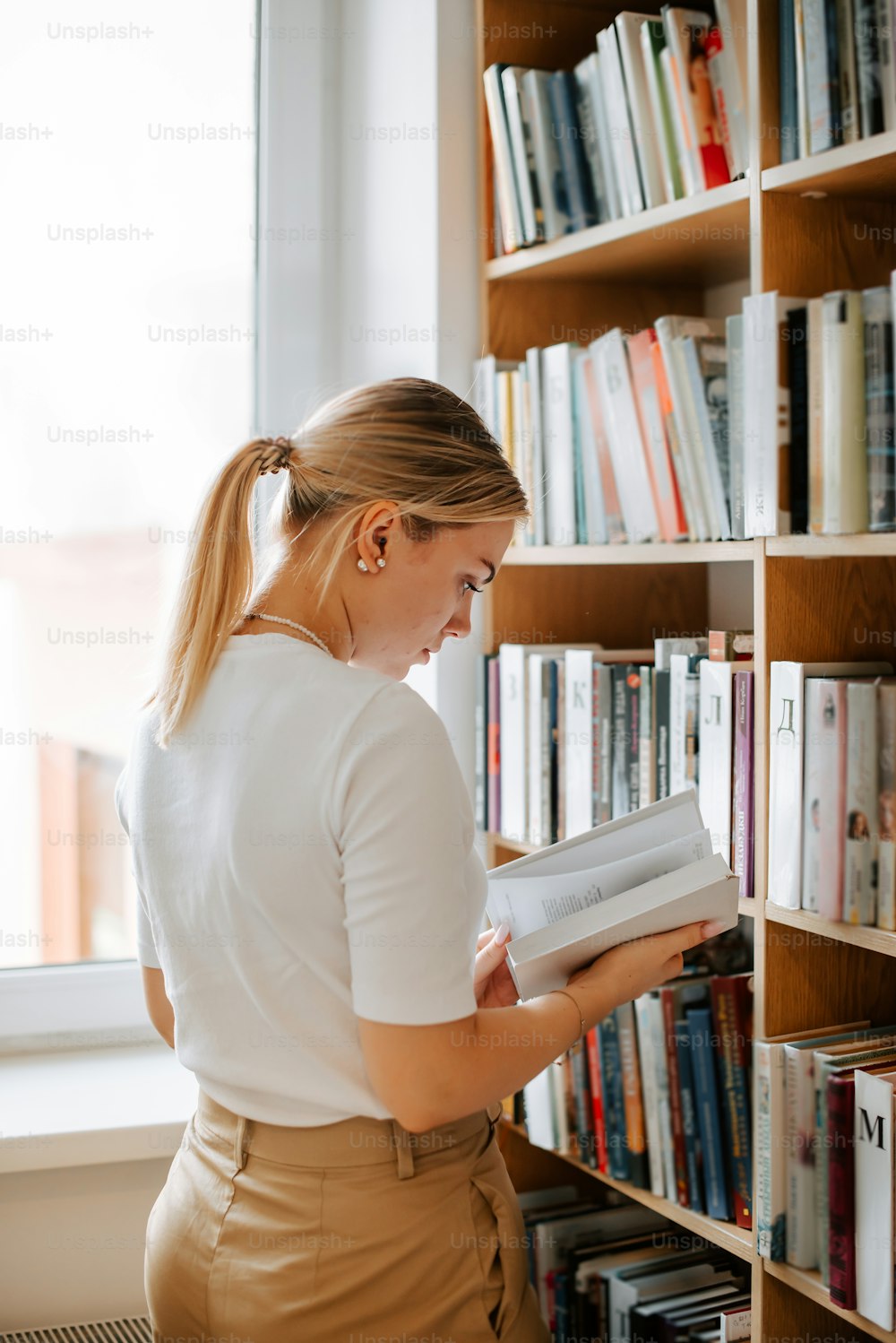 uma mulher lendo um livro em uma biblioteca