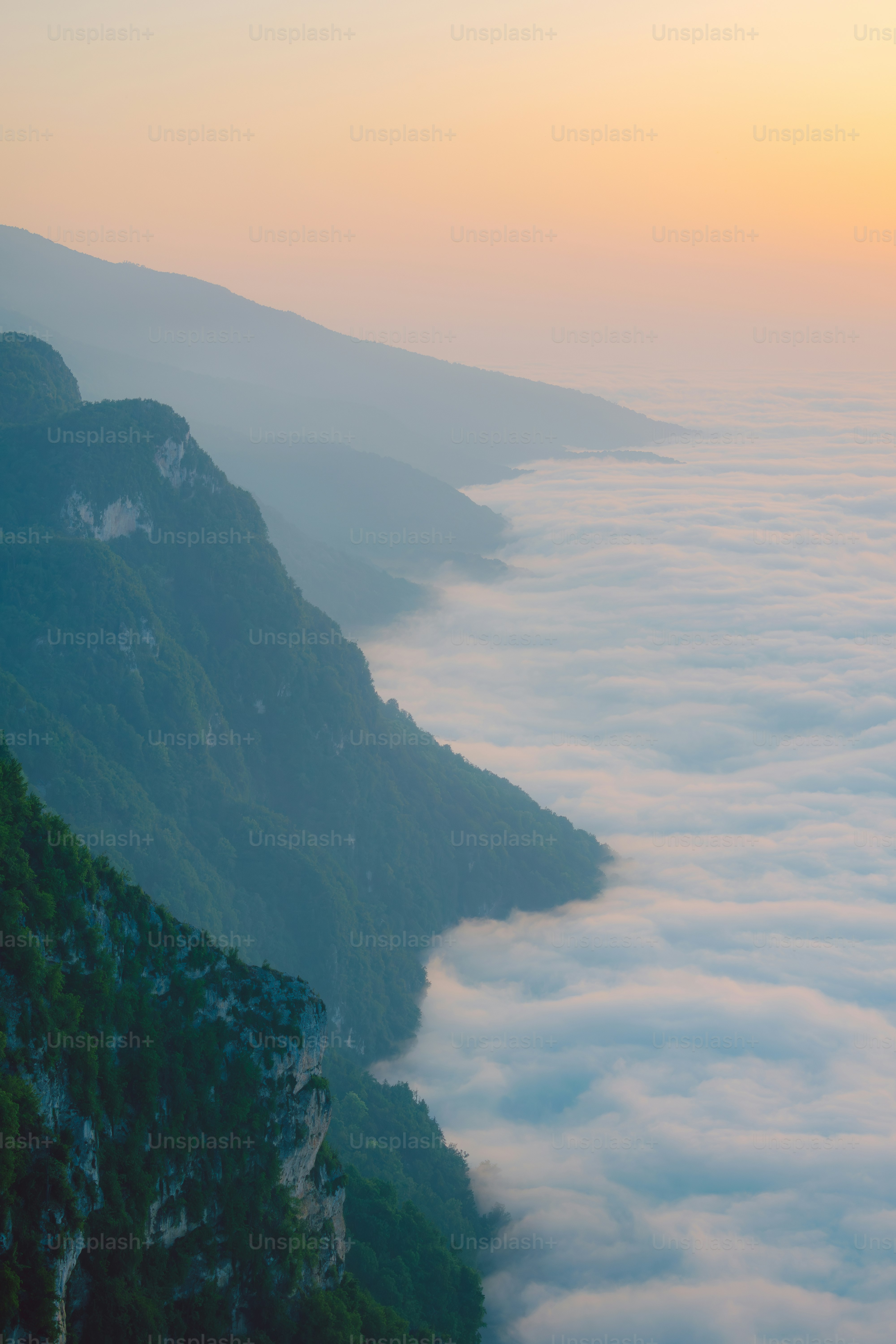 the sun is setting over the mountains above the clouds