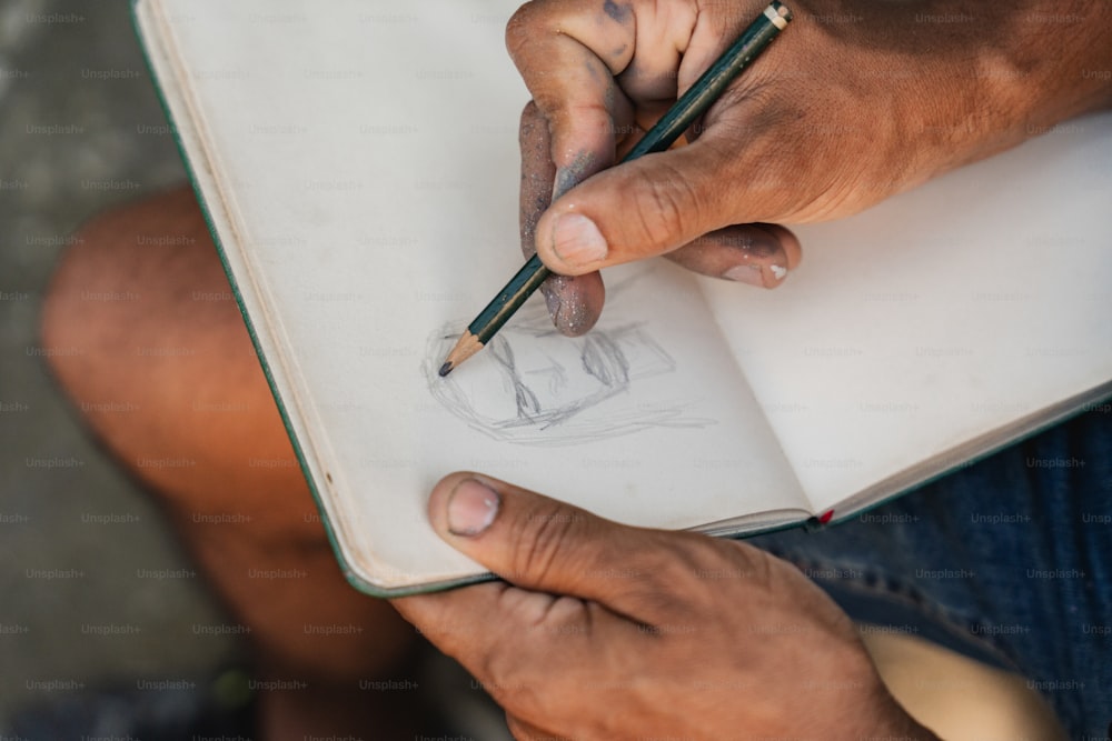 uma pessoa segurando um lápis e desenhando em um livro