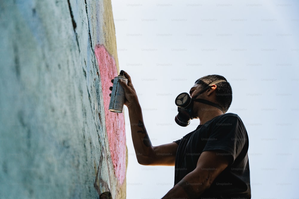 a man wearing a gas mask painting a wall