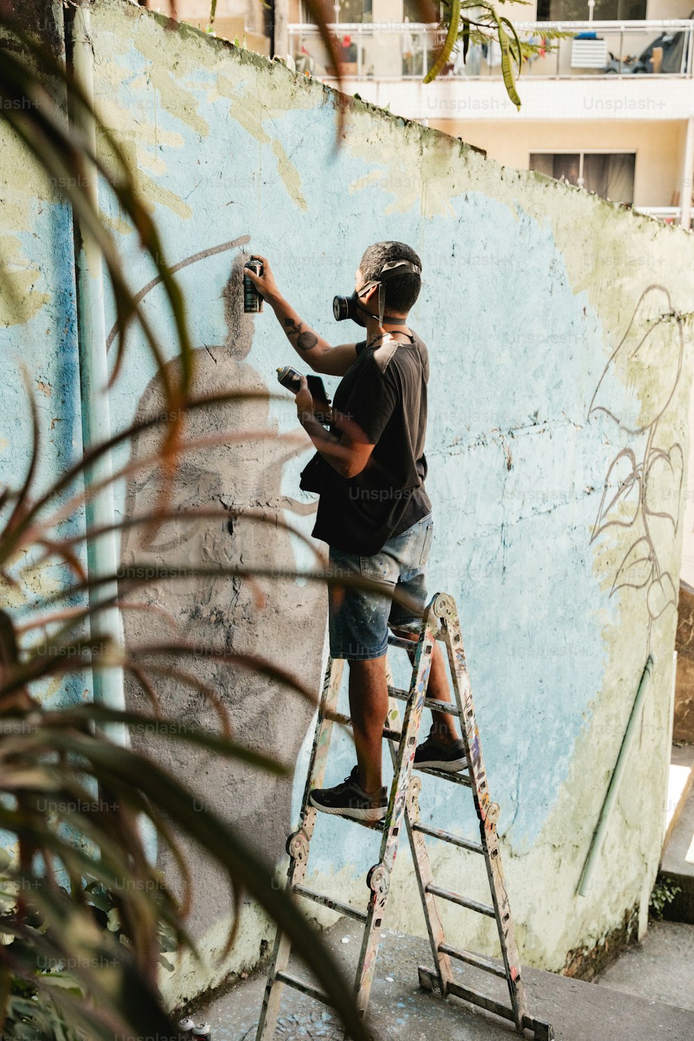 a man on a ladder painting a wall