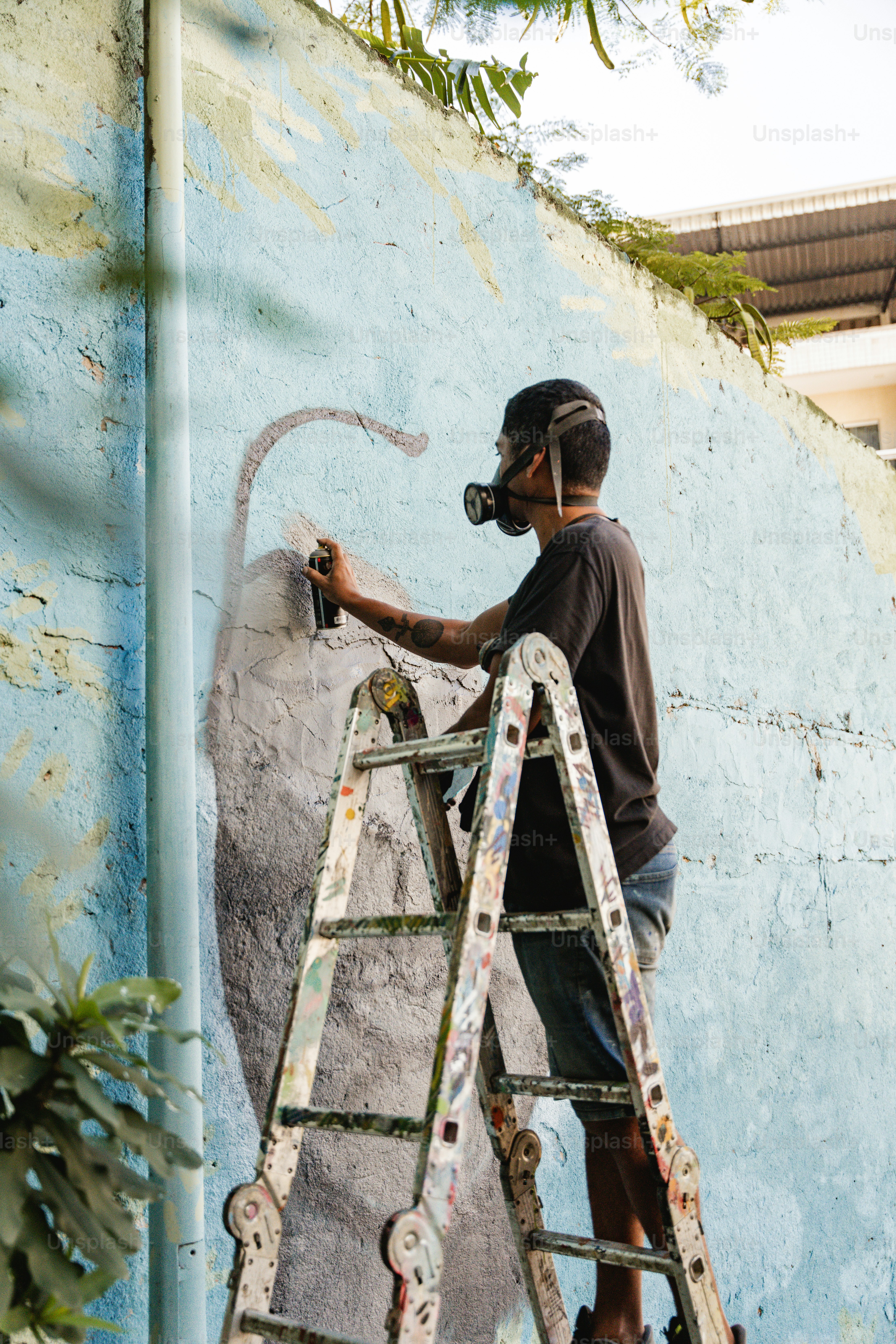 a man on a ladder painting a wall