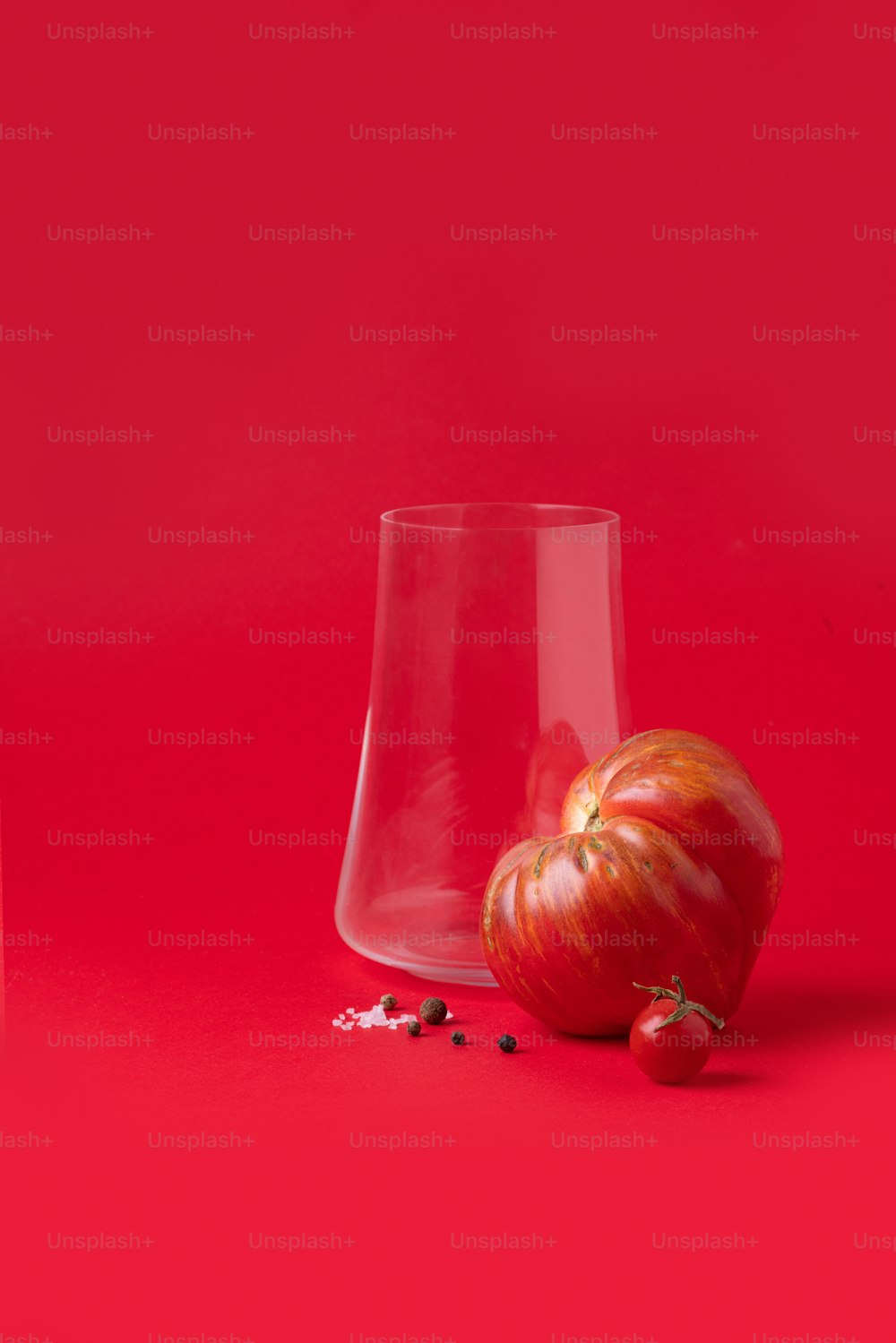 a red apple and a clear glass on a red background