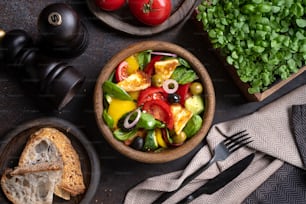 a bowl of salad next to a bowl of bread