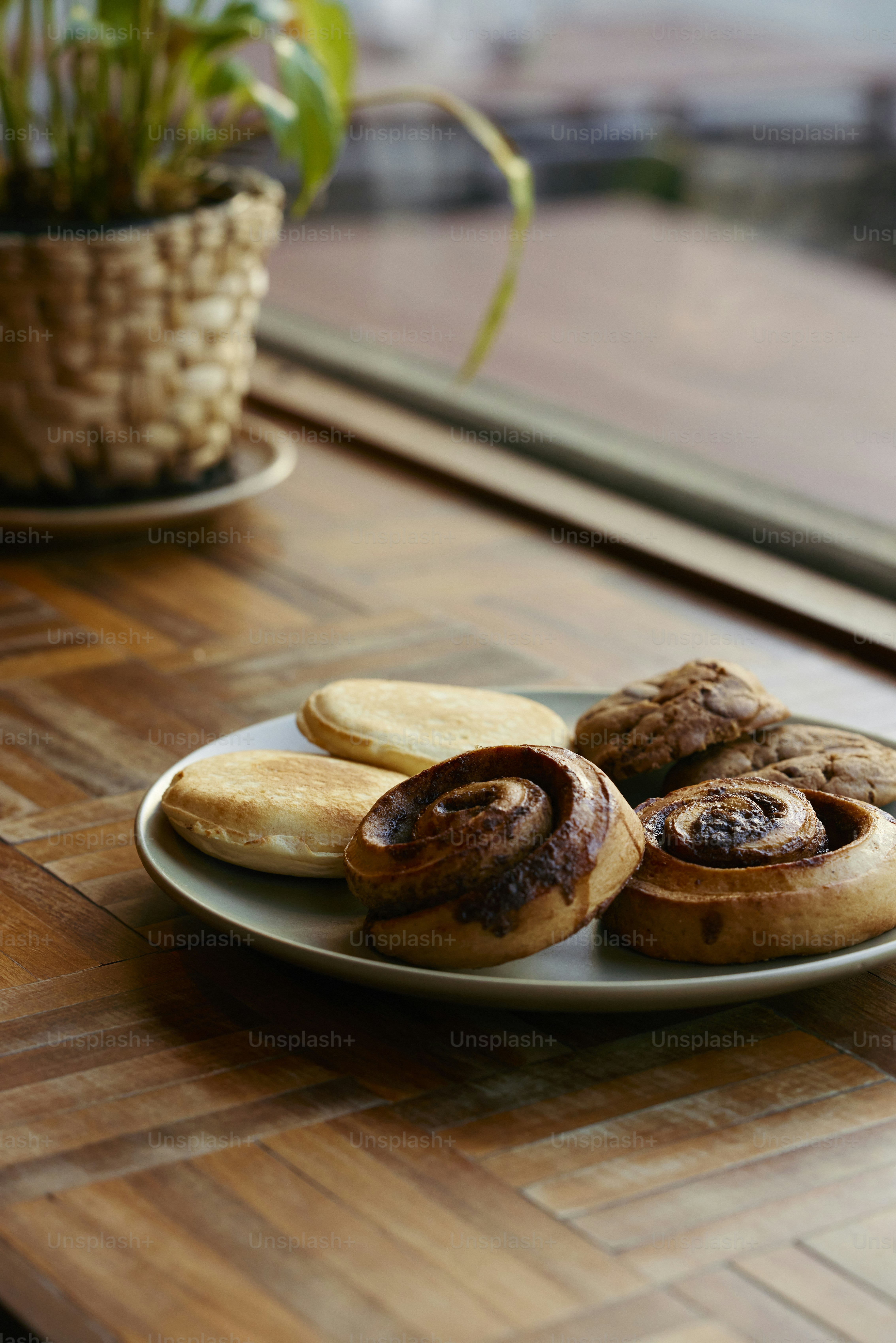 um prato de biscoitos sentado em uma mesa ao lado de um vaso de planta