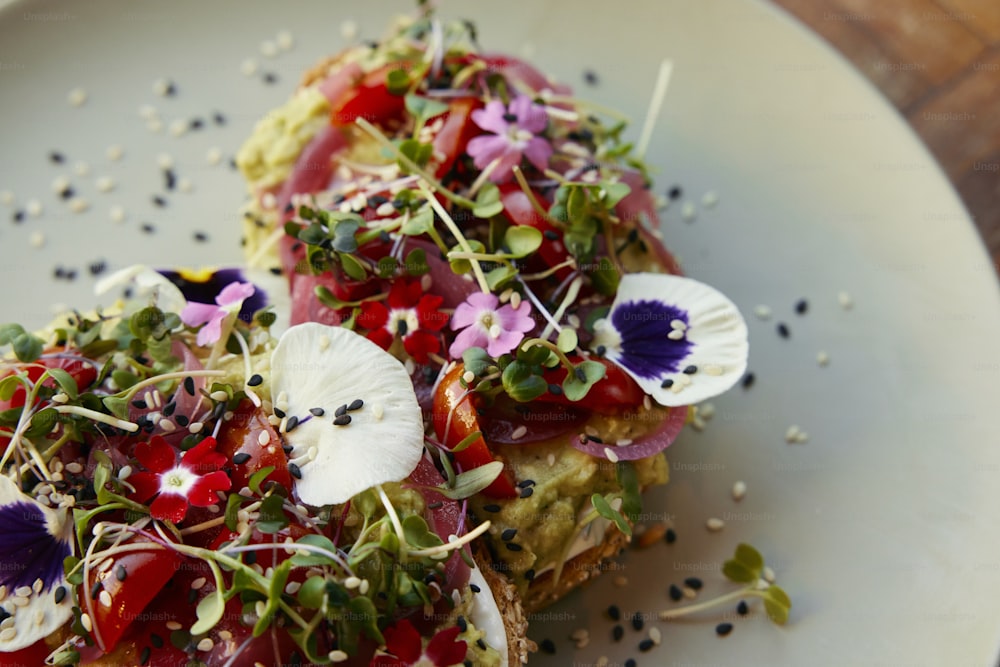 a white plate topped with two pieces of toast covered in veggies