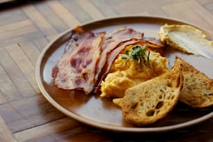 um prato de ovos, torradas e bacon sobre uma mesa