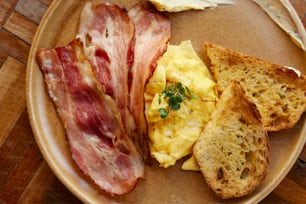 um prato com ovos, bacon e torradas
