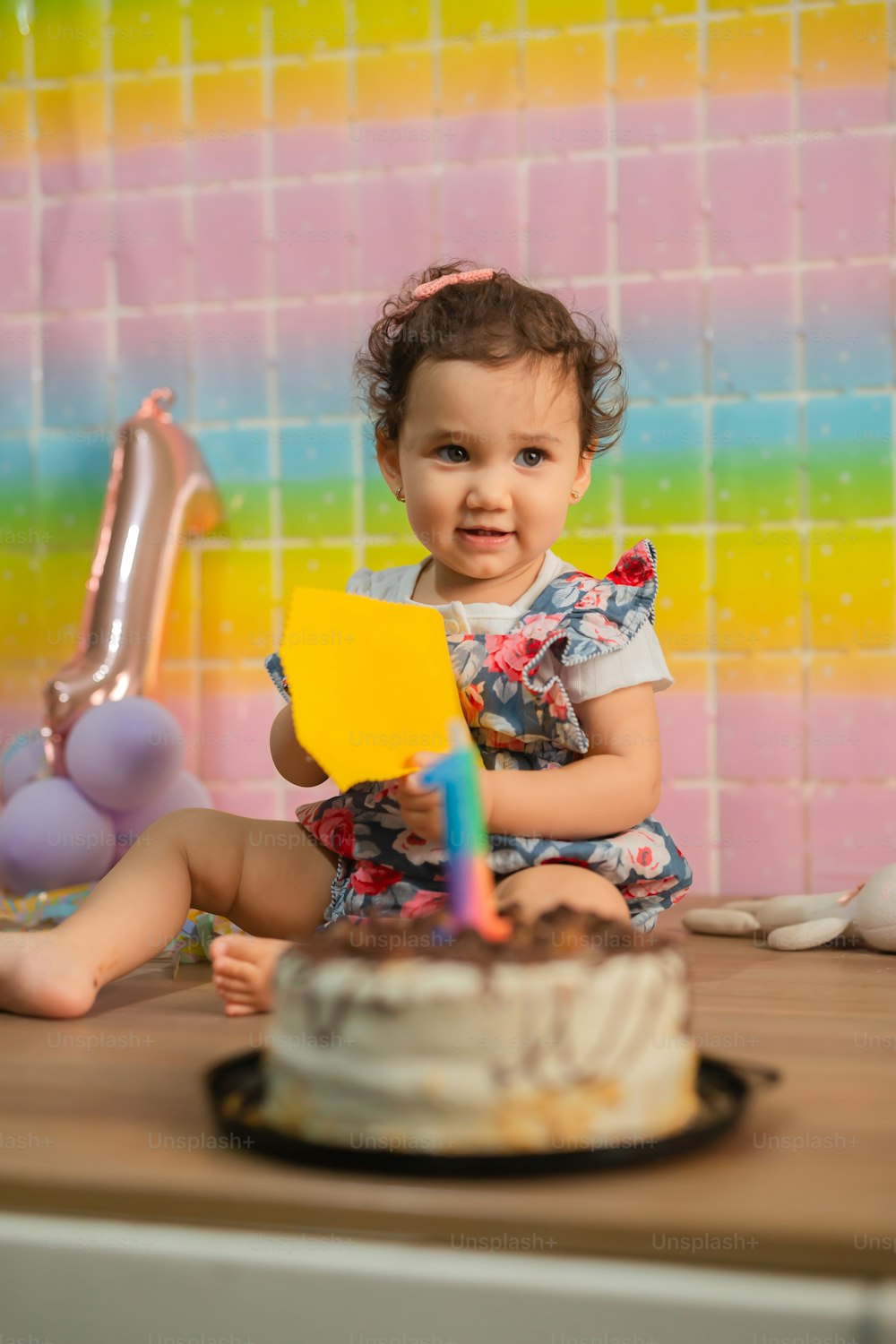 a little girl sitting in front of a birthday cake