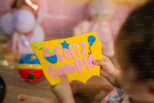 a child holding a sign that says feliz cumple