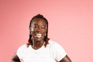 a smiling woman in a white t - shirt against a pink background