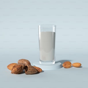 a glass of almond milk next to a pile of almonds