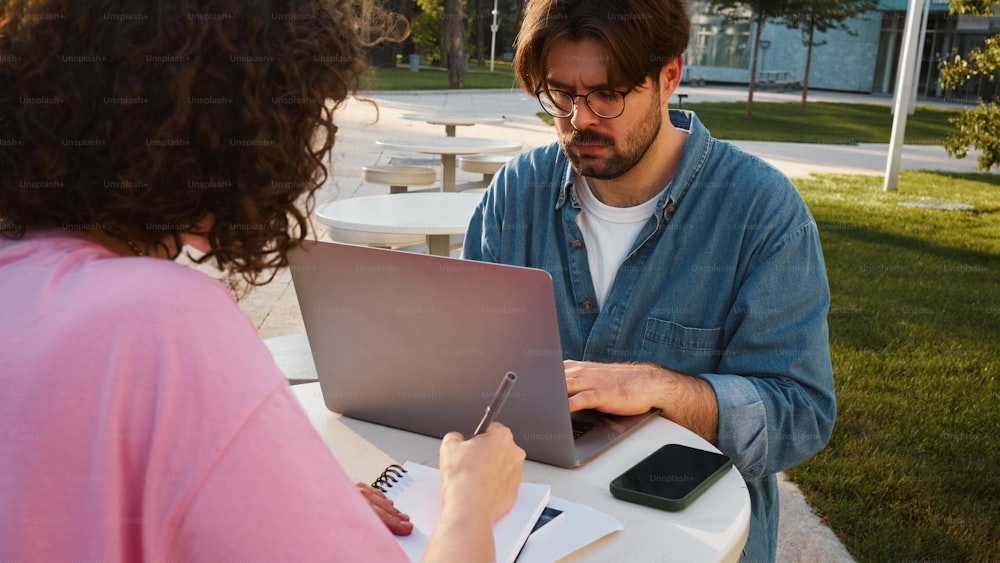 a man and a woman sitting at a table with a laptop