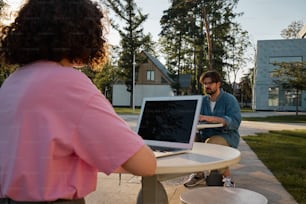 a man and a woman sitting at a table with a laptop