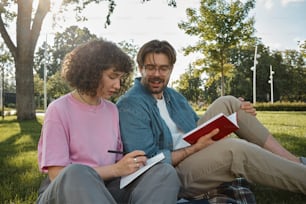 a man and a woman are sitting on the grass