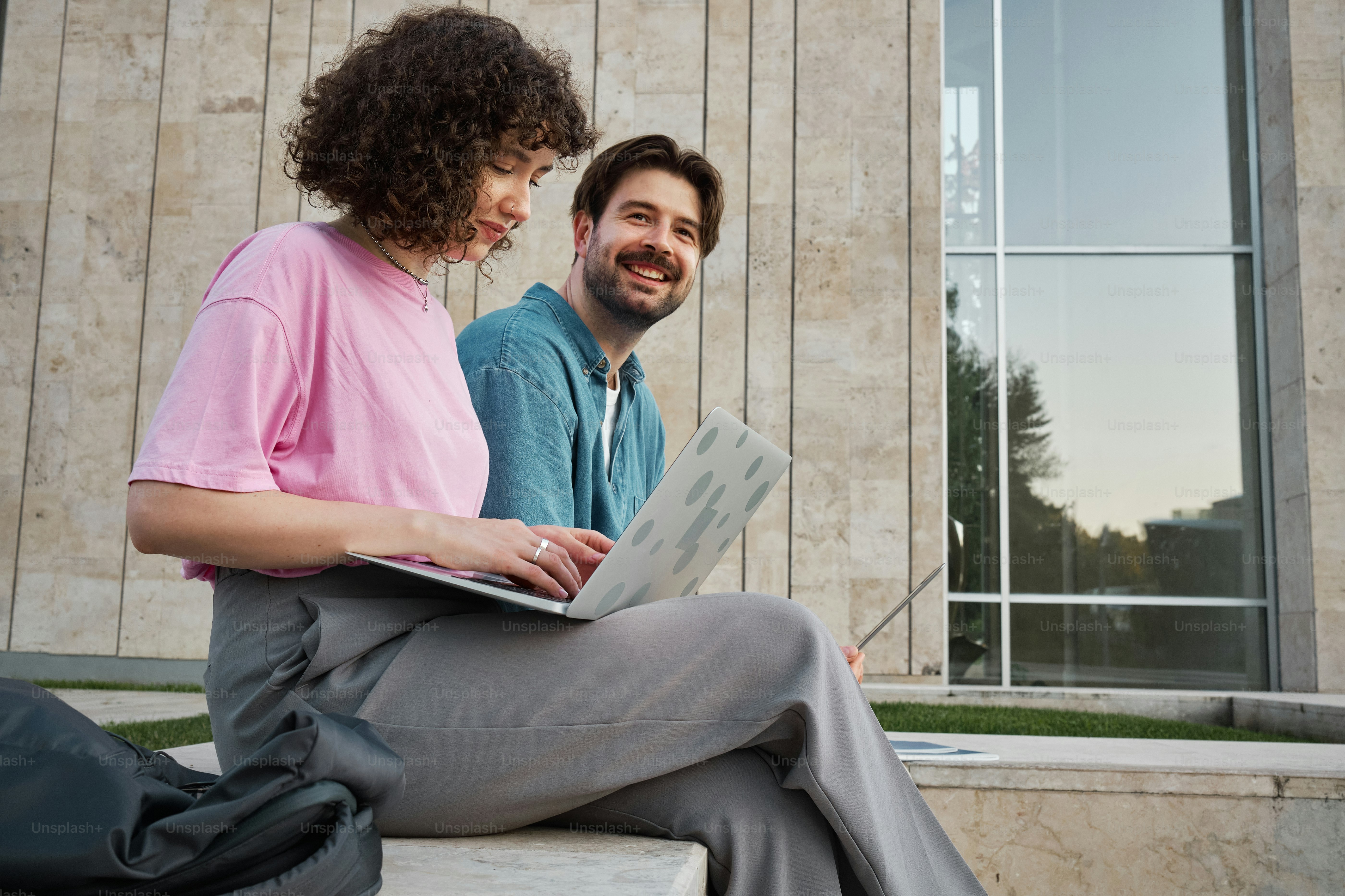 Un homme et une femme assis sur un banc regardant un ordinateur portable