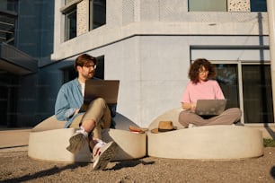 Un uomo e una donna seduti su un divano usando computer portatili