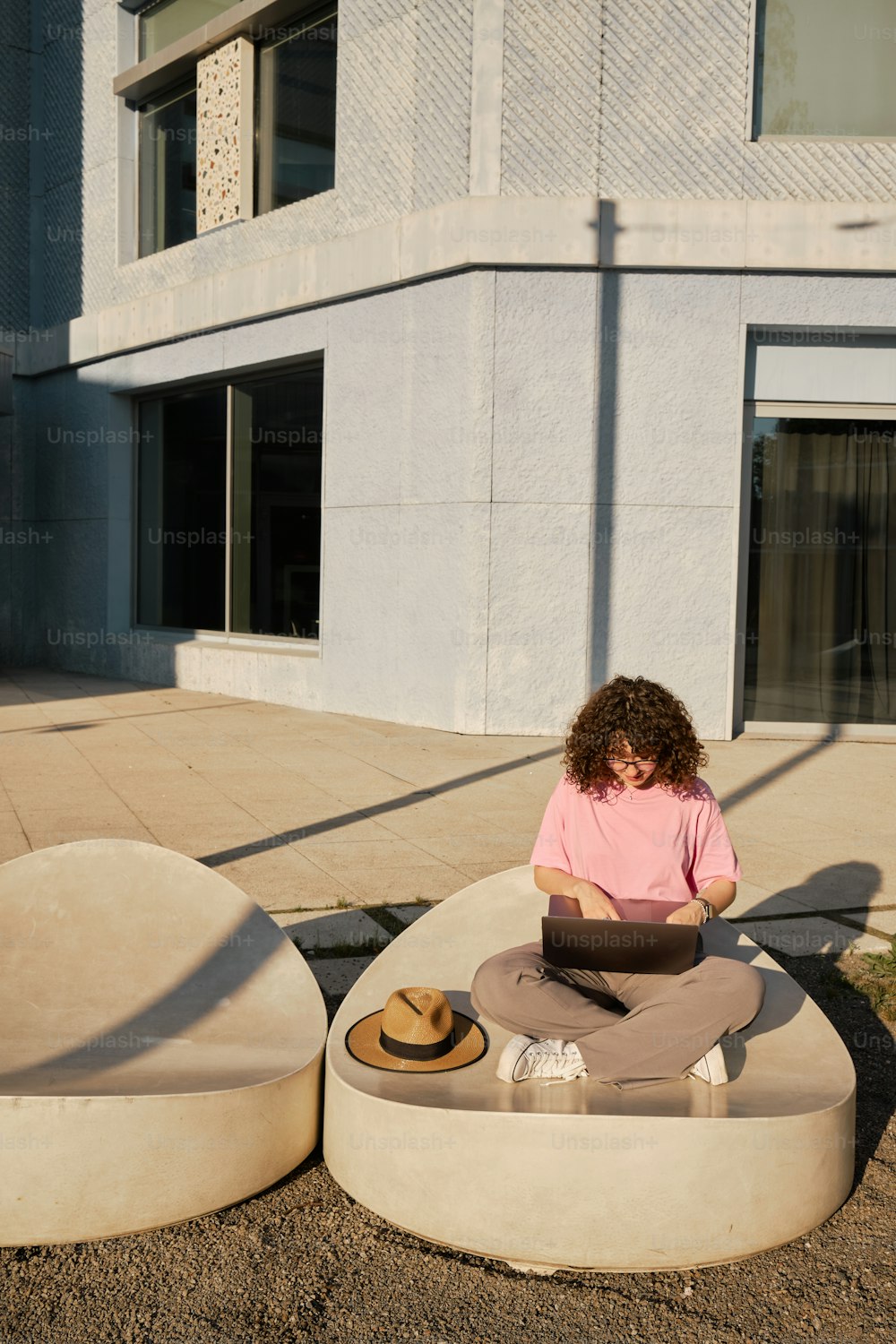 a woman sitting on a round bench using a laptop