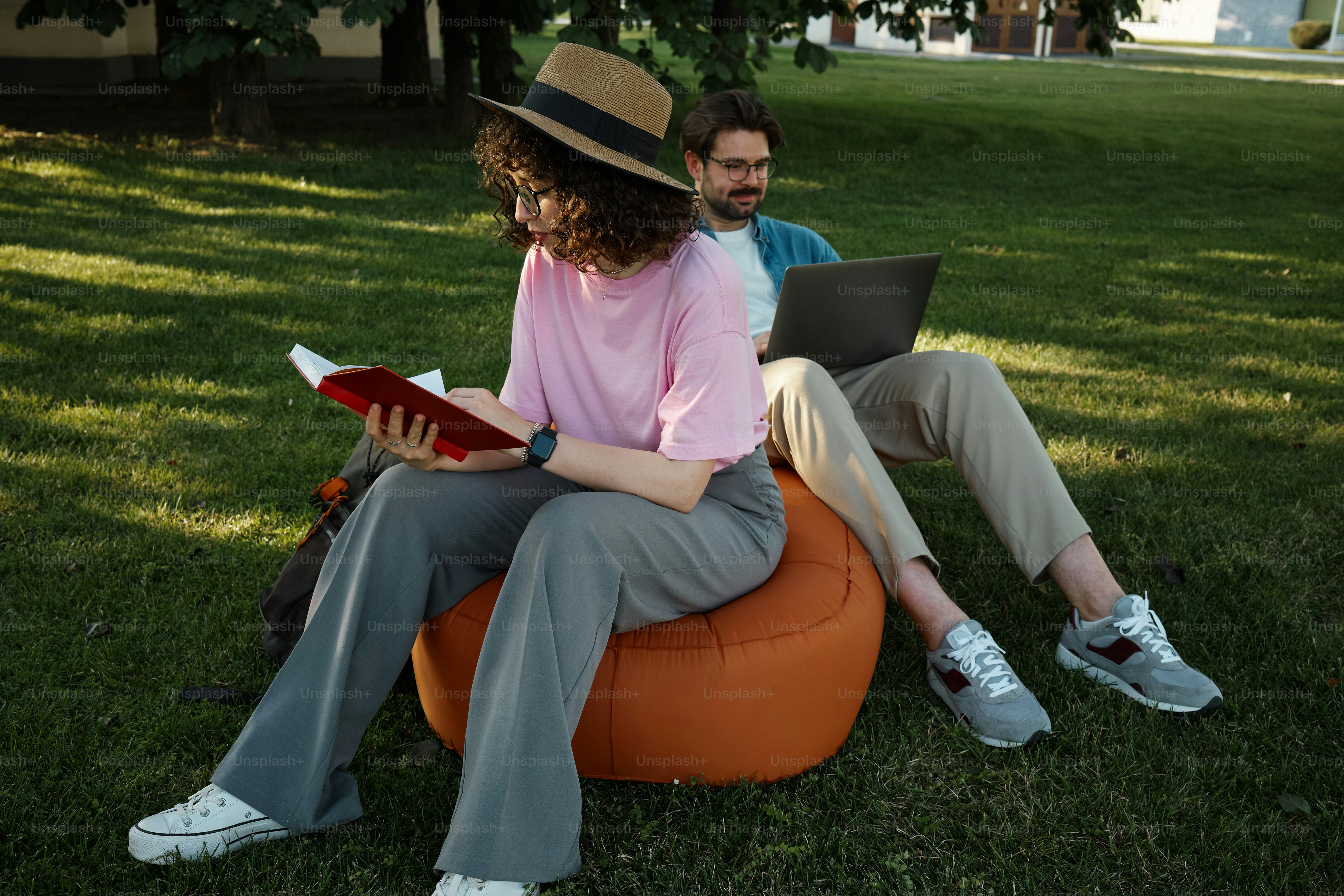 couple students relaxing on campus lawn on an inflatable chair