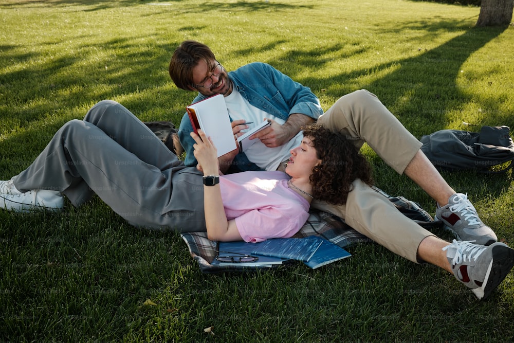 two people laying on the grass reading books