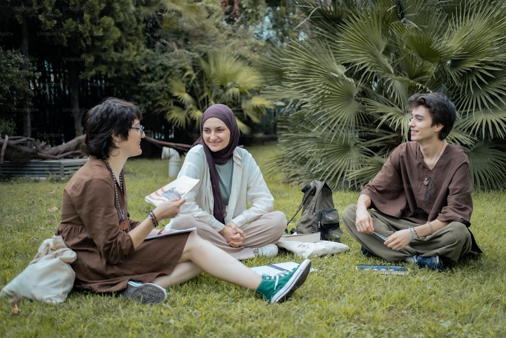 a group of people sitting on top of a lush green field