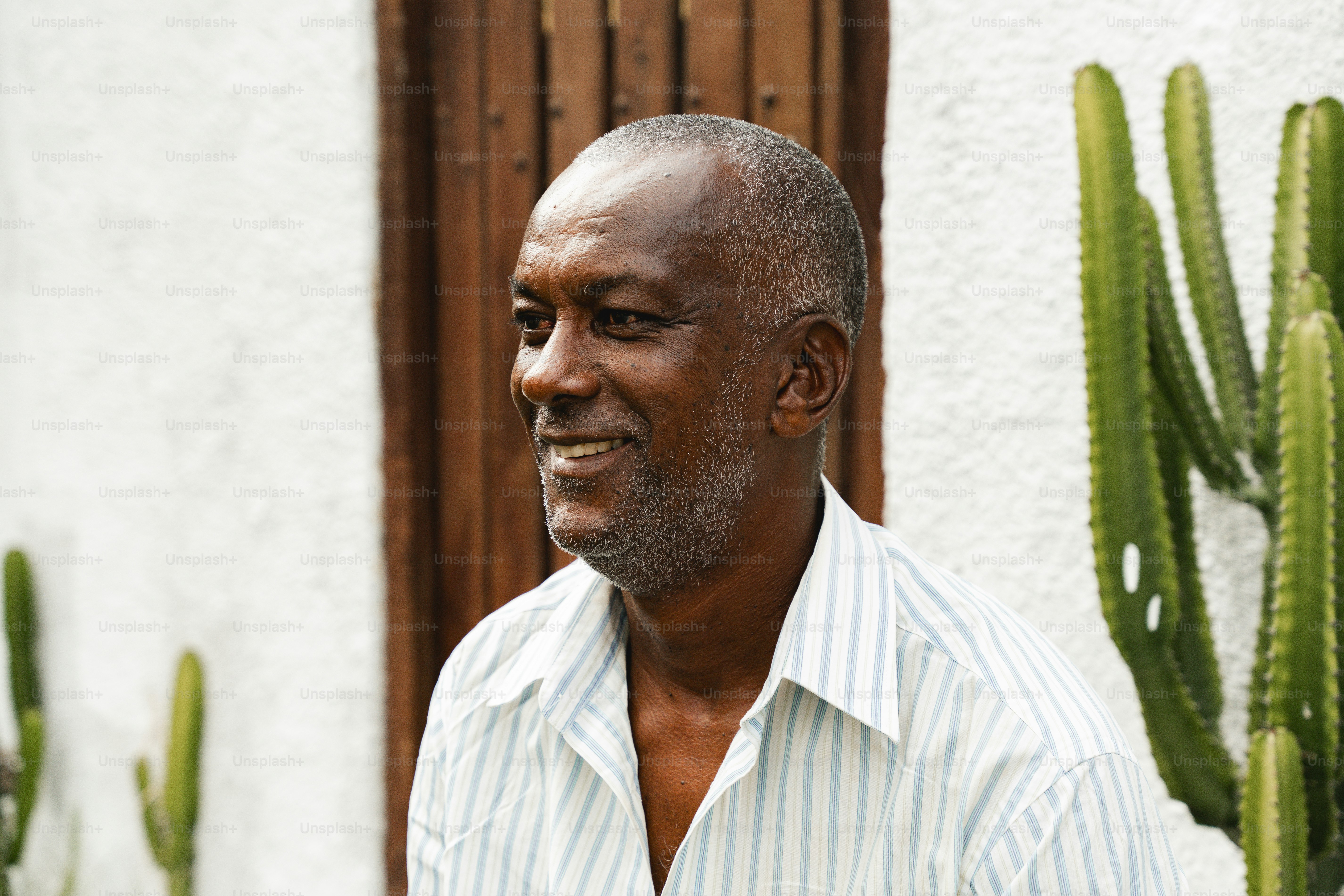 a man standing in front of a house next to a cactus