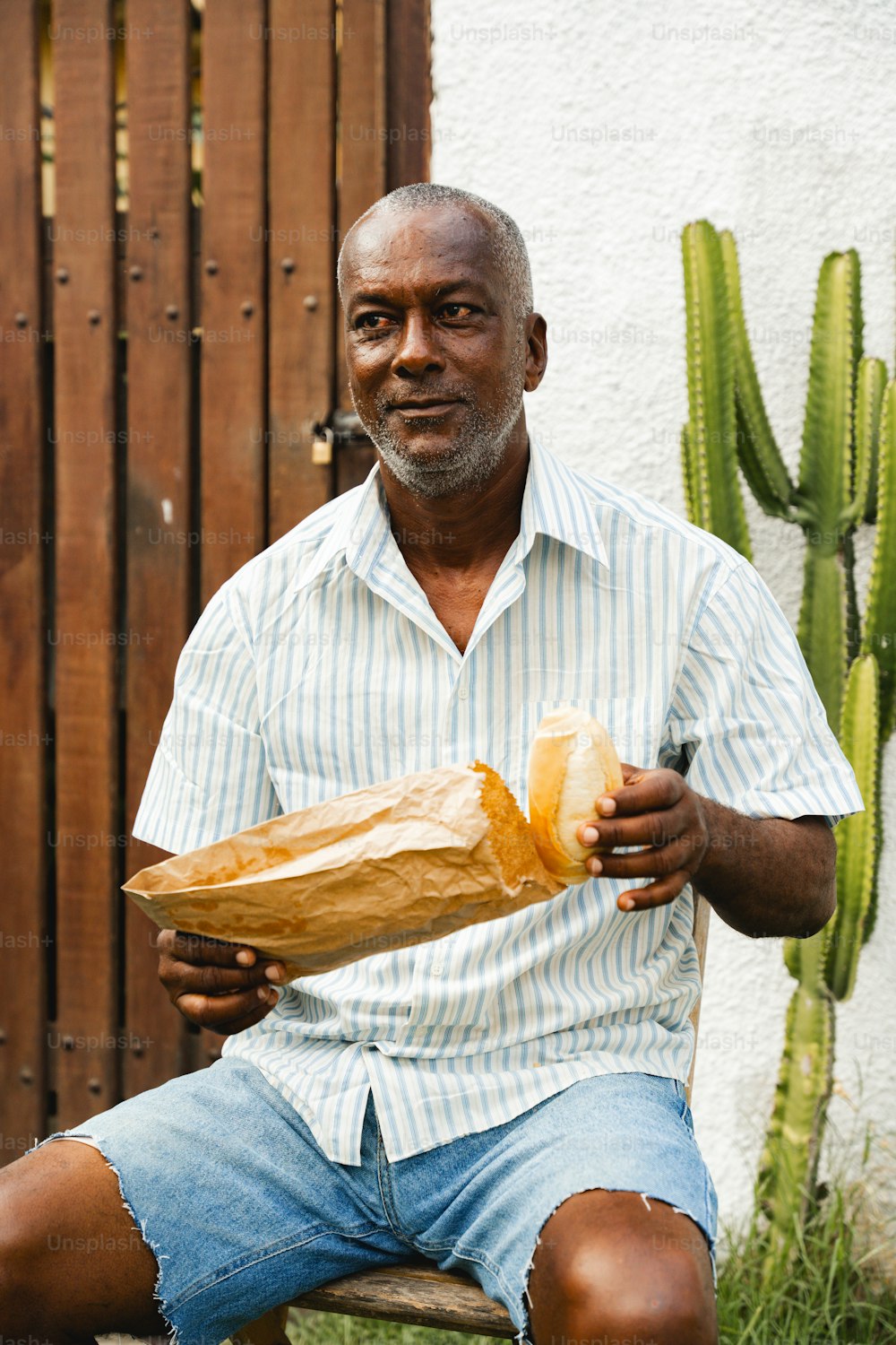 a man sitting on a bench holding a loaf of bread