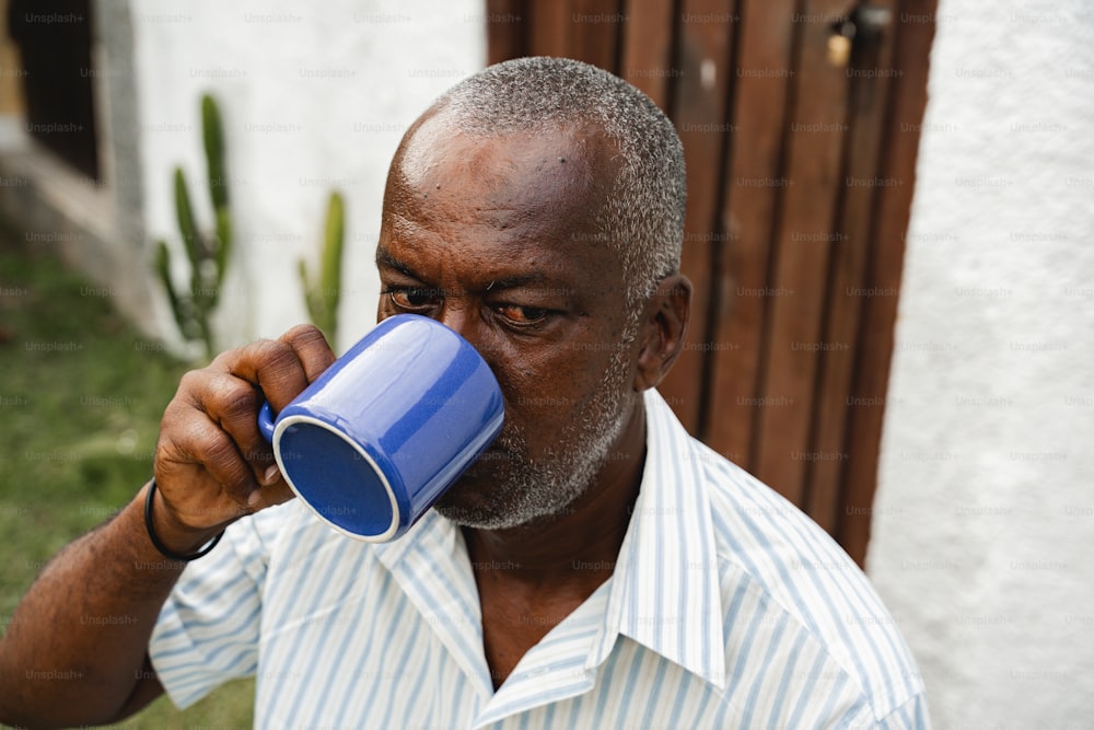 um homem bebendo uma xícara azul de café
