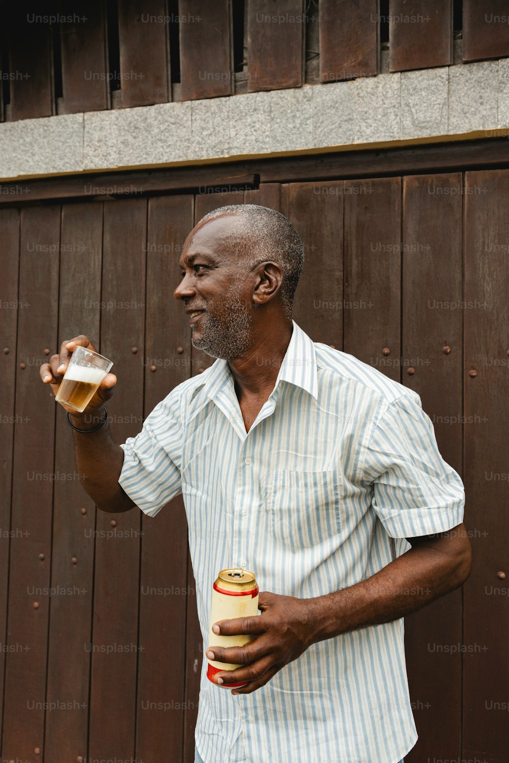 a man holding a beer and a sandwich