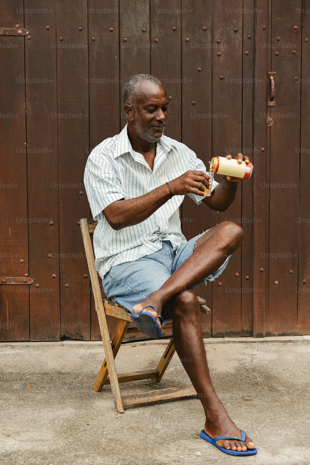 a man sitting on a chair eating a hot dog