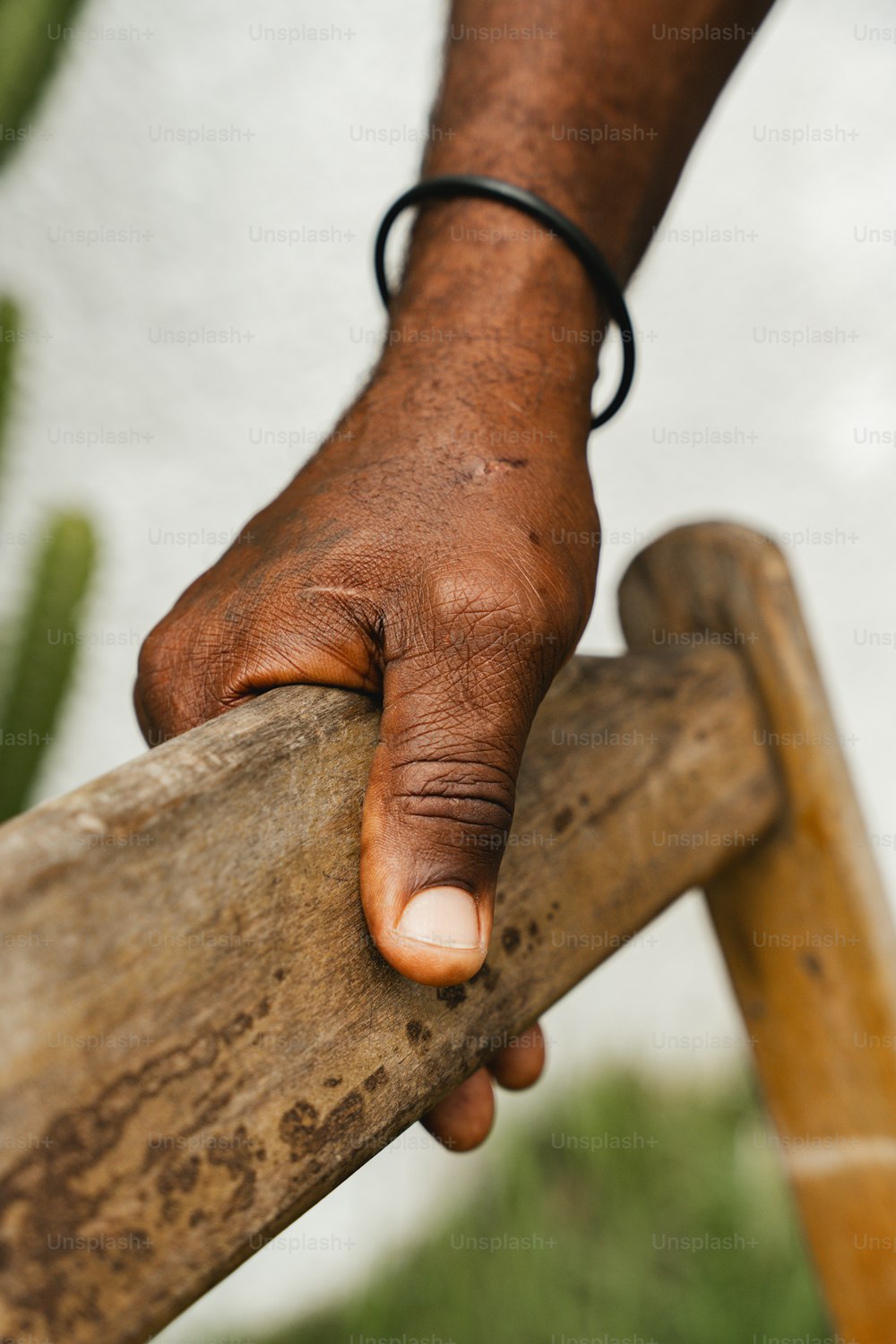 La mano de un hombre encima de una escalera de madera