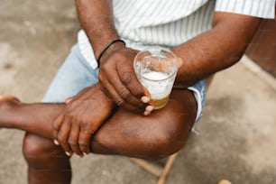 a man sitting down holding a glass of beer